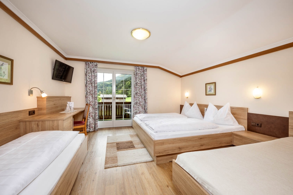 Helles, modernes Hotelzimmer mit drei Betten und Balkon