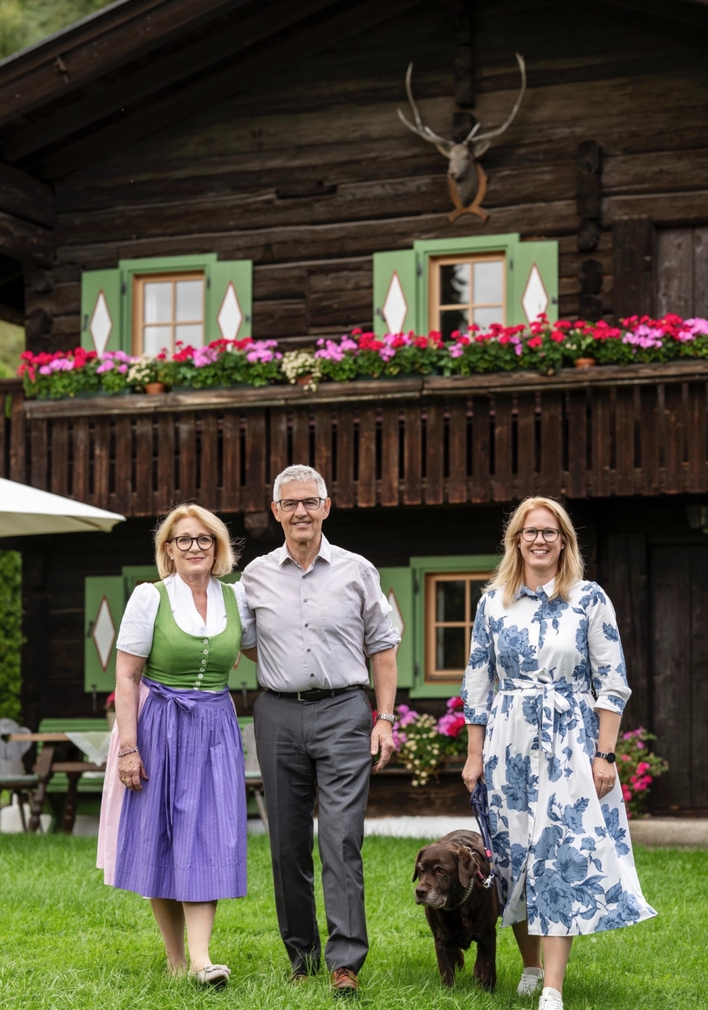 Familie Gschwandtner steht im Garten vor einem blühenden Hintergrund mit einem Hund.